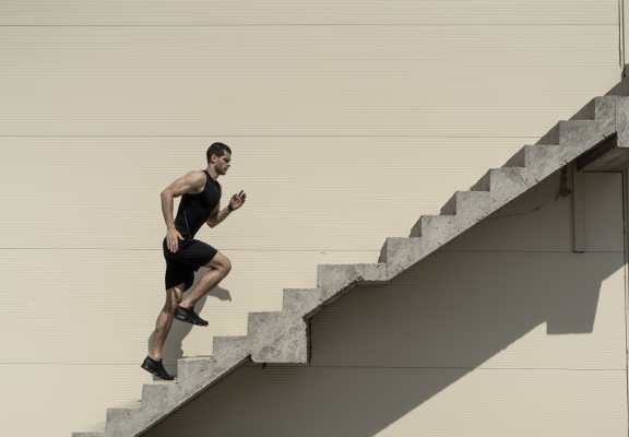 Up to top, overcoming challenges. Strong athletic man climbing stairs.