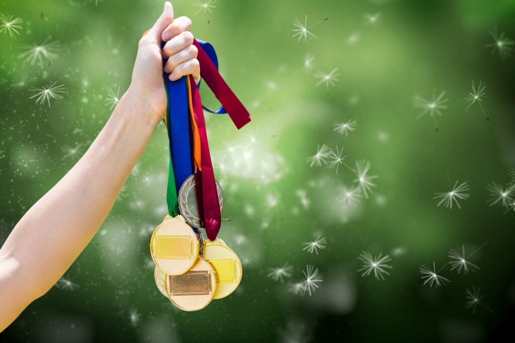 composite of hand holding medals over nature background.|21.|Tag2.|Link-1.