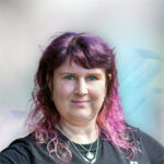 Porträt einer Person mit lila Haaren, die direkt in die Kamera schaut, vor einem sanften, verschwommenen Hintergrund.