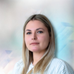 Porträt einer Frau mit blonden Haaren und blauen Augen, vor einem verschwommenen, farbigen Hintergrund.