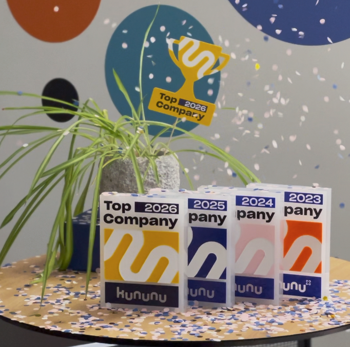 Ausgezeichnete Kununu-Trophäen „Top Company“ 2023-2026 auf einem Tisch mit Dekoration und Pflanze.